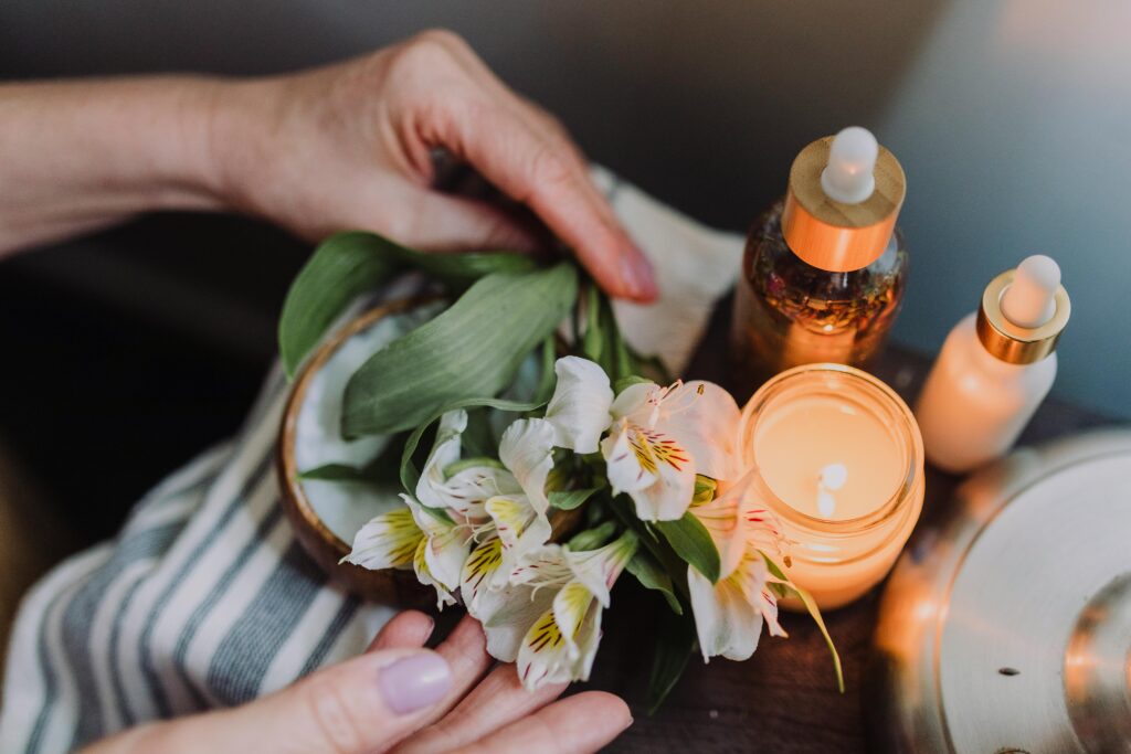 Ambient candlelit setting with hands arranging delicate white flowers, evoking tranquility.